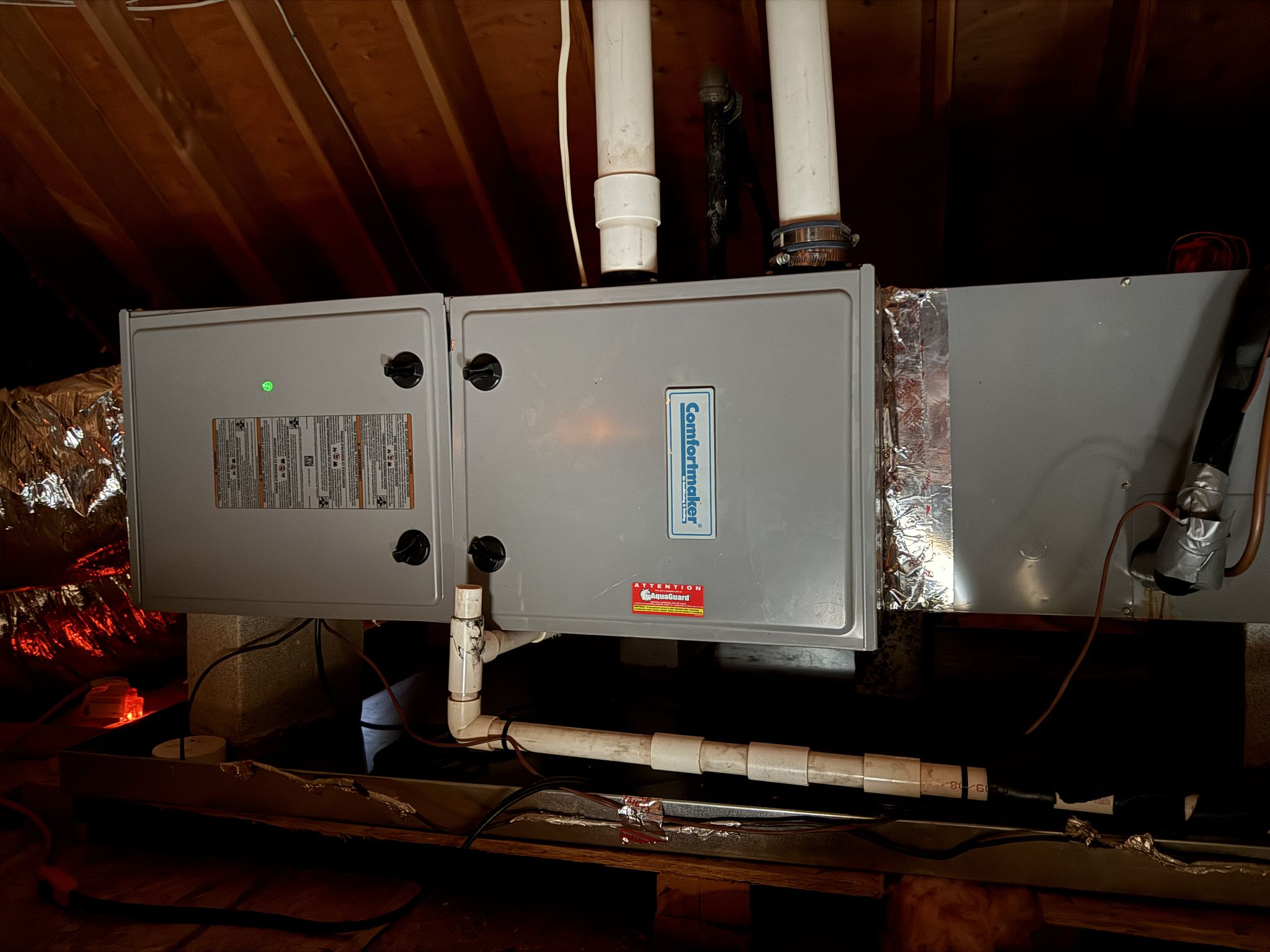 Horizontal Comfortmaker furnace in an attic with ductwork and white piping