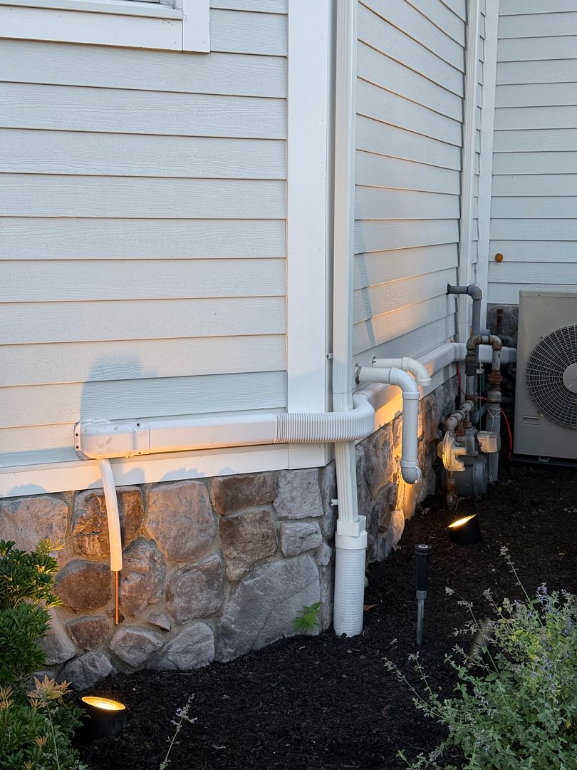 White HVAC line-set covers routed along exterior siding beside an outdoor unit