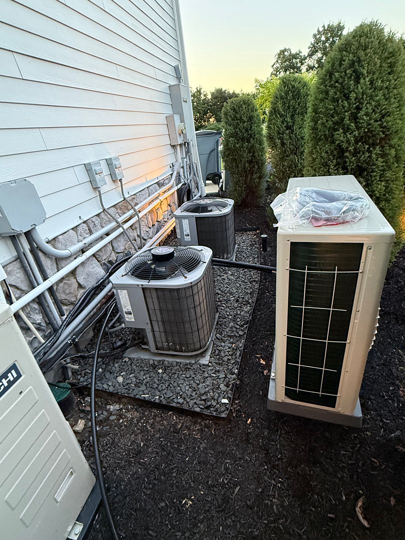 Multiple outdoor condensers and HVAC units along the side of a house